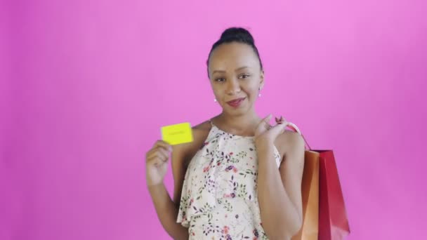 Donna afroamericana con carta di credito e pacchi in mano. Un backgound rosa. Abito bianco con fiori
 - Filmati, video