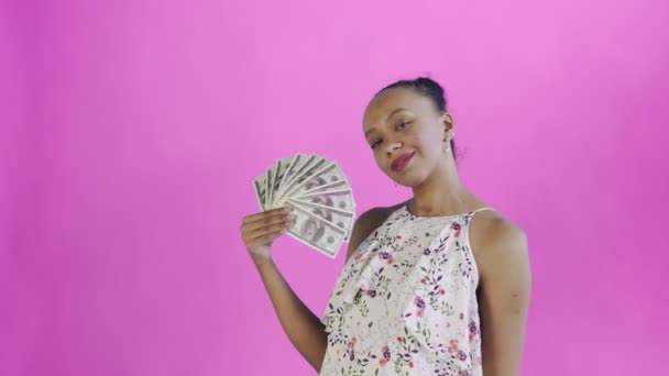 African american woman with money fan on pink Background in Studio. White dress with flowers - Materiał filmowy, wideo