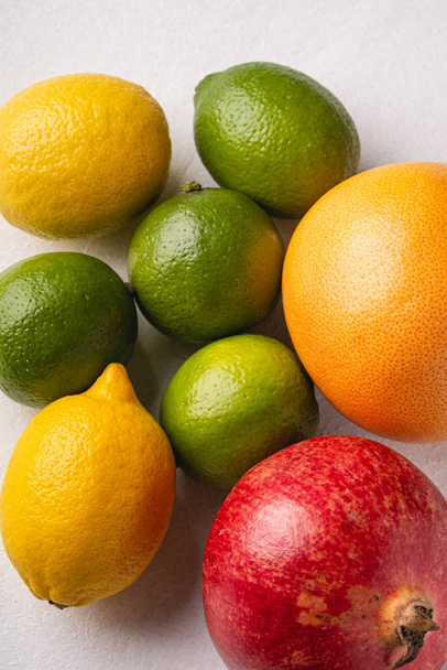 Lime, lemon, grapefruit and pomegranate on white background, angle view, macro, vitamins and healthy food - Fotó, kép