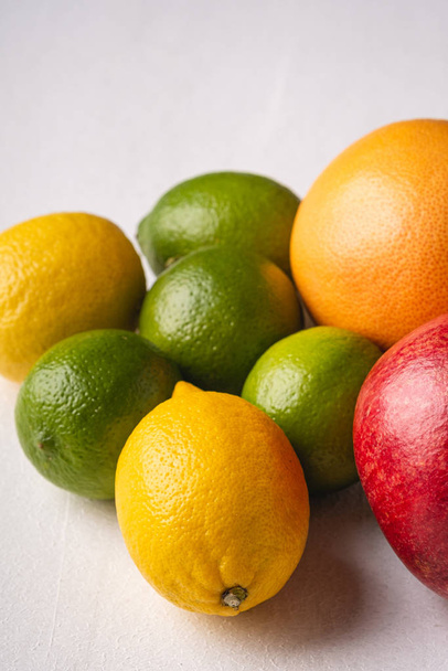 Lime, lemon, grapefruit and pomegranate on white background, angle view, macro, vitamins and healthy food - Zdjęcie, obraz