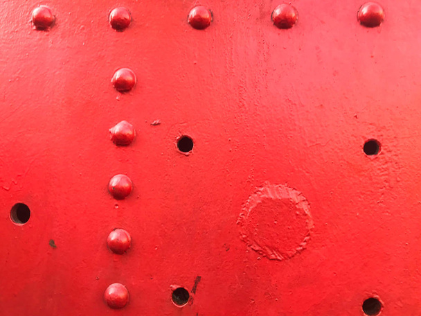 Red iron metal rough painted strong solid industrial wall with rivet holes and bolts. Background, texture - Photo, Image
