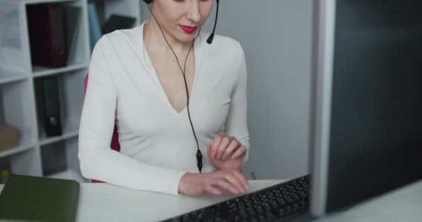 Atraktivní mladá žena zákaznický servis agent mluví se zákazníkem s telefonním sluchátkem, jak se dívá do kamery - Záběry, video