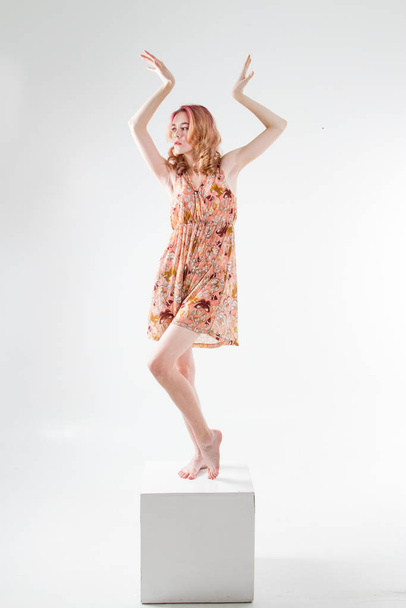 Νεαρή όμορφη κοπέλα στέκεται στο ξυπόλητο κύβο και σε ένα φόρεμα - Φωτογραφία, εικόνα