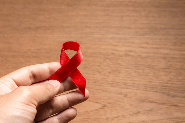 Mano con cinta roja Sensibilización sobre el sida para el Día Mundial del VIH / SIDA. - Foto, imagen