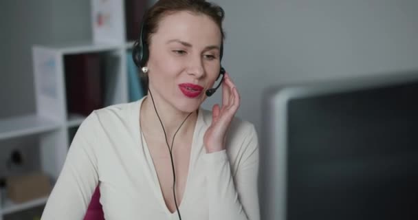 コールセンターの女性従業員ヘッドセットによって呼び出し顧客との会話の幸せ - 映像、動画