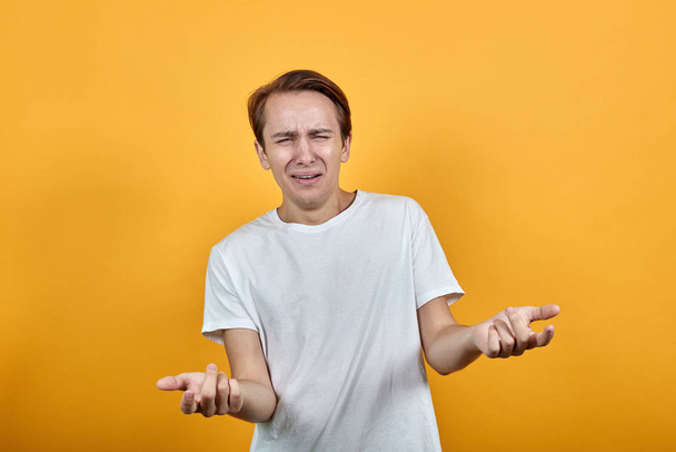Ideges síró férfi fehér ingben sárga háttér gesztikulál a kezével. - Fotó, kép