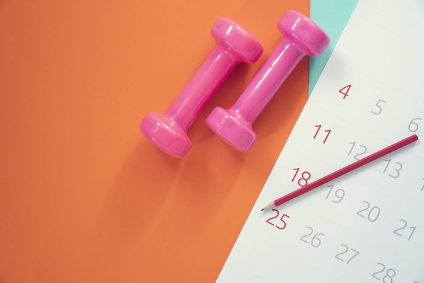 Time for exercising calendar and dumbbell with colorful backgrou - Foto, afbeelding