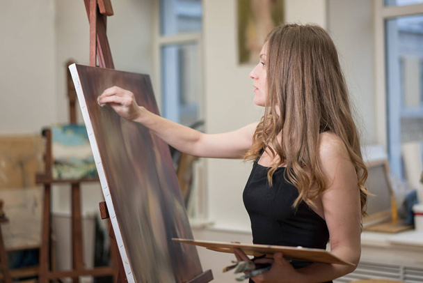 Γυναίκα καλλιτέχνης αντλεί από τον καμβά στο στούντιο τέχνης, πορτρέτο προφίλ. - Φωτογραφία, εικόνα