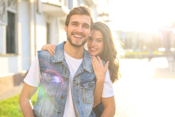 Beautiful young couple in love walking outdoors at the city street, hugging. - Foto, Imagen