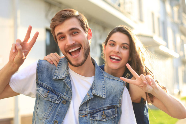 Image of a happy smiling cheerful young couple outdoors take a selfie by camera showing peace. - Foto, Imagen
