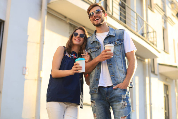Image of lovely happy couple in summer clothes smiling and holding hands together while walking through city street. - Foto, imagen