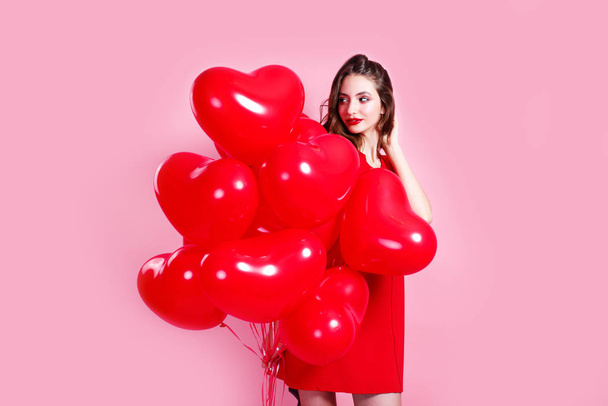 happy young woman celebrating Valentines day, holding red balloons on pink background - Φωτογραφία, εικόνα