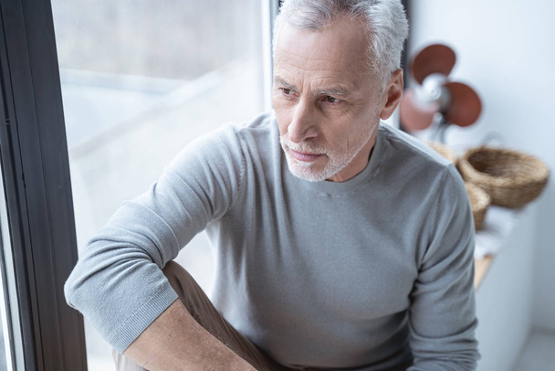 Serious mature man by the window stock photo - Photo, image