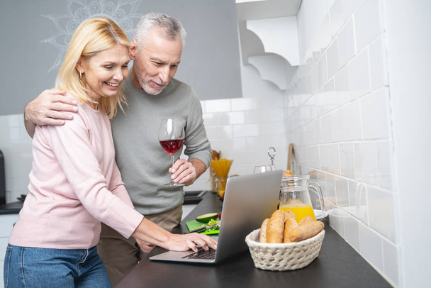 Happy couple with laptop in the kitchen stock photo - Foto, Imagen