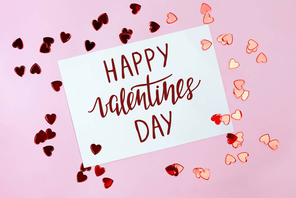 Valentijnsdag wenskaart en kleine rode hartjes over roze achtergrond - Foto, afbeelding