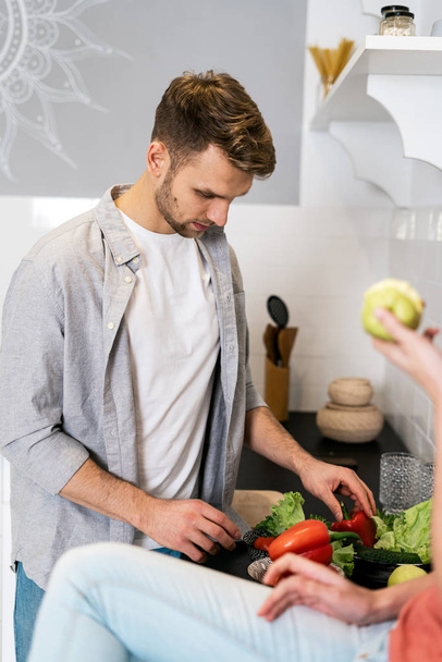 Jonge volwassen man en vrouw staan in de moderne keuken - Foto, afbeelding