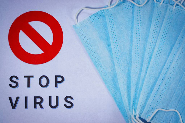 Προστατευτικές ιατρικές μάσκες σε λευκό φόντο με τις λέξεις Stop Virus και το σύμβολο "Απαγορευμένη" - Φωτογραφία, εικόνα