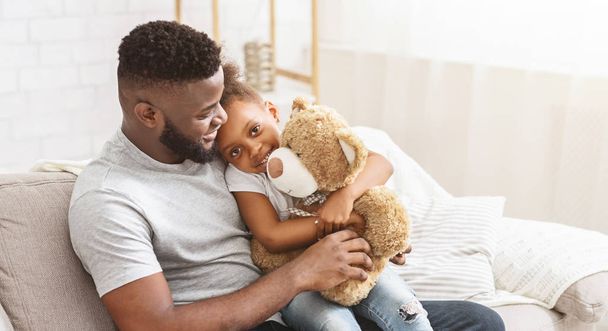 Siyah baba ve kızı evdeki kanepede oturuyor. - Fotoğraf, Görsel
