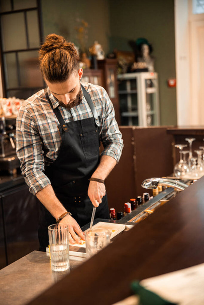 Young bearded barman preparing ingredients for drinks - Foto, afbeelding