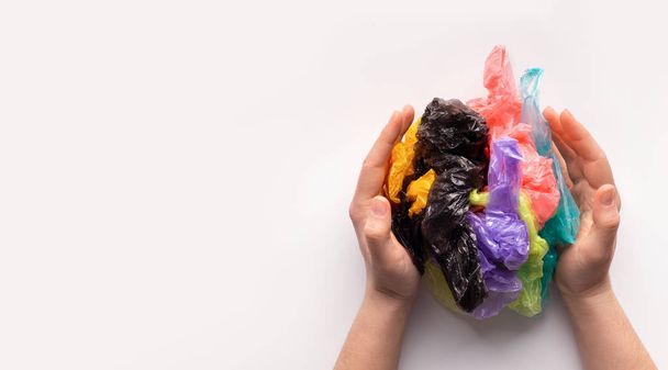 Γυναικεία χέρια που κρατούν χρωματιστές πλαστικές σακούλες σε σύνθεση μπάλας - Φωτογραφία, εικόνα
