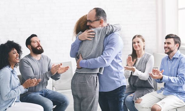 Positive people hugging during group therapy session in rehab - Фото, изображение