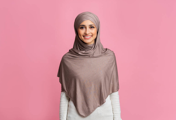 Portrait of beautiful muslim woman in hijab posing over pink background - Fotó, kép