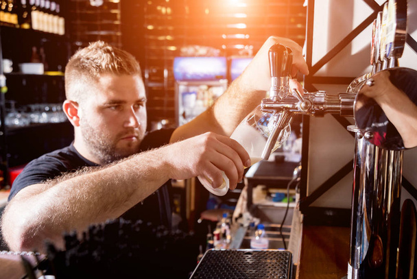 Bartender pouring draft beer at glasses in the bar. Restaurant. - Fotó, kép
