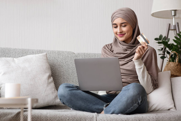 Donna musulmana in velo con computer portatile e carta di credito a casa
 - Foto, immagini