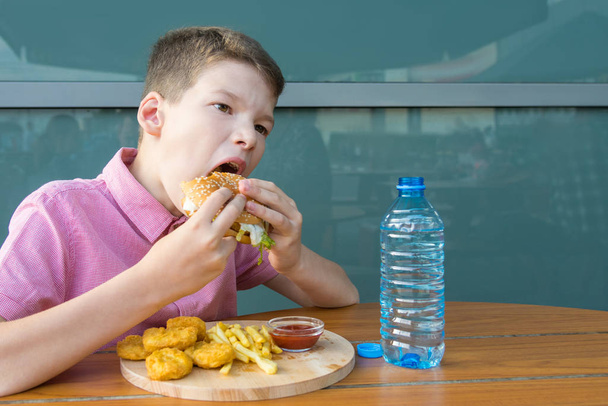 boy having lunch in a fast food restaurant eating a burger - Foto, imagen