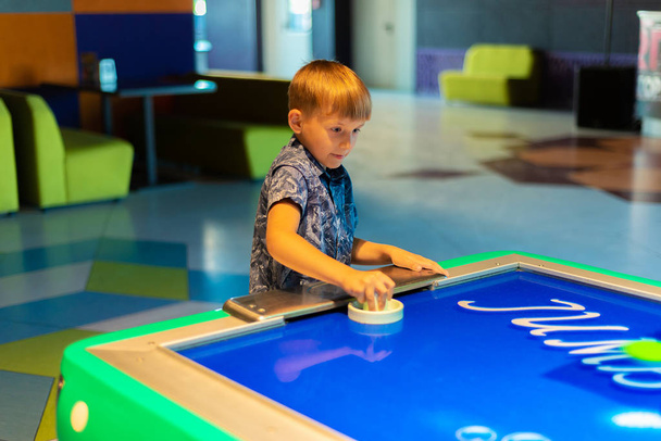 The child plays air hockey in the children's entertainment center. - Photo, Image