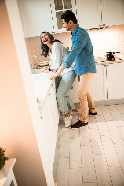 Smiling man and woman having fun while standing on the kitchen - Foto, immagini