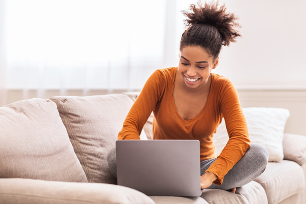 Feliz señora usando el ordenador portátil de trabajo desde casa sentado en el sofá
 - Foto, Imagen