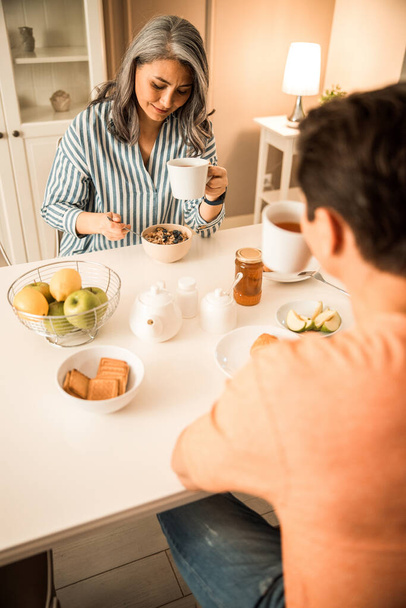 Adult man and woman drinking tea and sitting at home - Foto, afbeelding