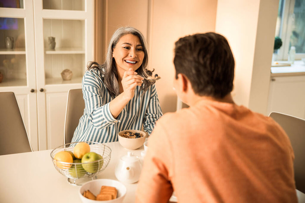 Uśmiechnięta kobieta karmi męża w domu - Zdjęcie, obraz
