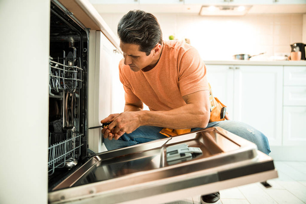 Man is repairing appliances in the kitchen - Foto, Imagen