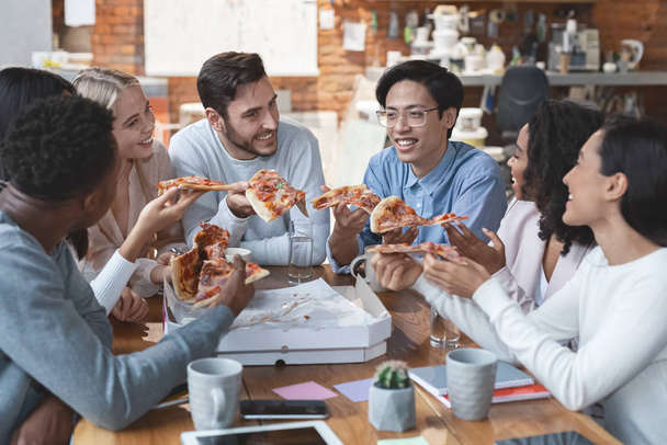 Jeunes collègues bavardant tout en mangeant de la pizza au bureau
 - Photo, image