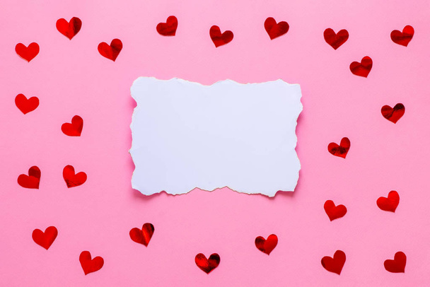 Λευκή άδεια λίστα χαρτιού με κόκκινες καρδιές κομφετί σε ροζ φόντο - Φωτογραφία, εικόνα