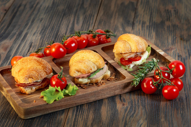 Croissants with cream, tomatoes and herbs on wooden background - Fotó, kép