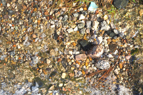 Kis kavicsok és homok a tiszta víz rétegei alatt. Felülnézet, közelkép - Fotó, kép