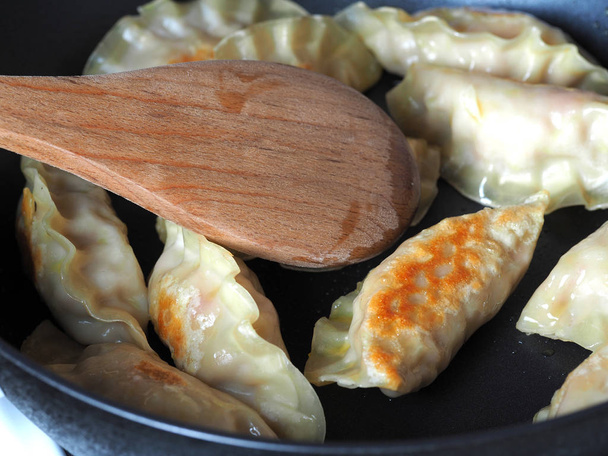 Las albóndigas se fríen en una sartén. Plato asiático con una variedad de rellenos. Gyoza frita
 - Foto, Imagen