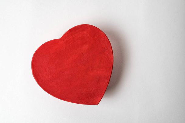 Caja roja en forma de corazón sobre el fondo blanco. Directamente arriba. Regalo para el día de San Valentín
 - Foto, imagen