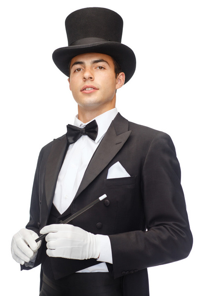 Magician in top hat with magic wand showing trick - Fotó, kép
