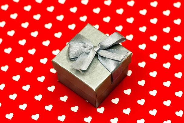 small gray gift box on white and red hearts background. Valentine's Day, wedding, love, happiness concept - Fotó, kép
