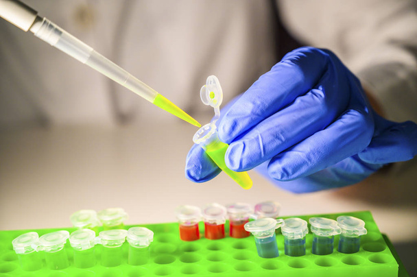 Ученый вынимает зеленый химический раствор из трубки Эппендорфа
 - Фото, изображение