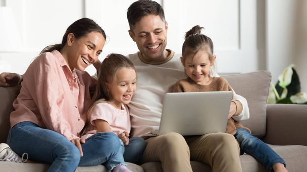 Happy young family enjoy video on laptop together - Фото, зображення
