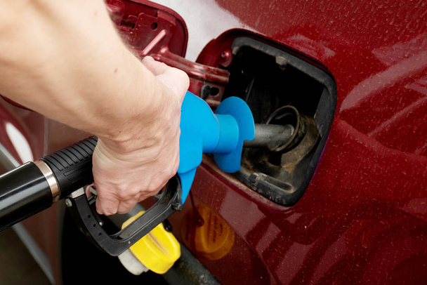 A man hand holding pump filling gasoline. Pumping petrol into the tank. A car refuel on gas station - Фото, изображение