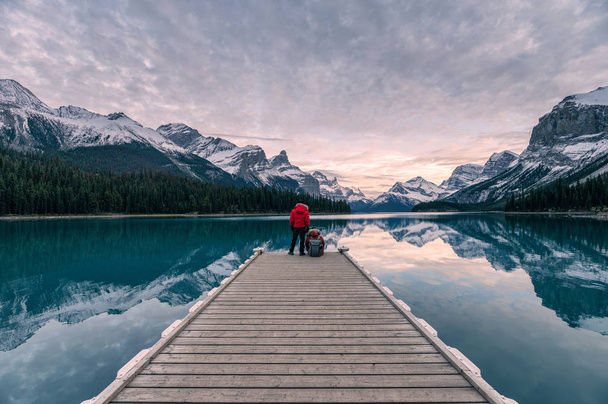 Couple traveler relaxing on wooden pier in Maligne lake at Spiri - Фото, изображение