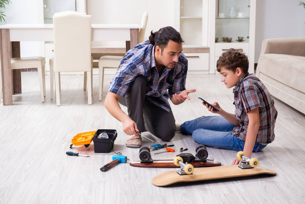 Молодий батько ремонтує скейтборд зі своїм сином вдома
 - Фото, зображення