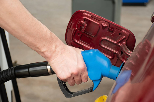 Мужчина держит насос, наполняющий бензин. Заливаю бензин в бак. Автозаправка на заправке - Фото, изображение