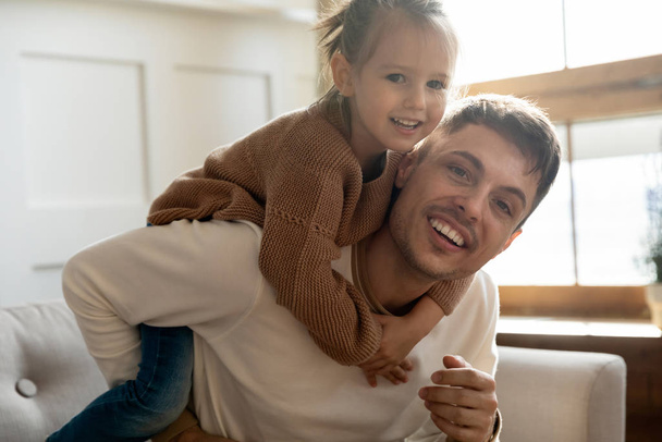 Portrait of happy little kid piggyback smiling dad - Foto, afbeelding